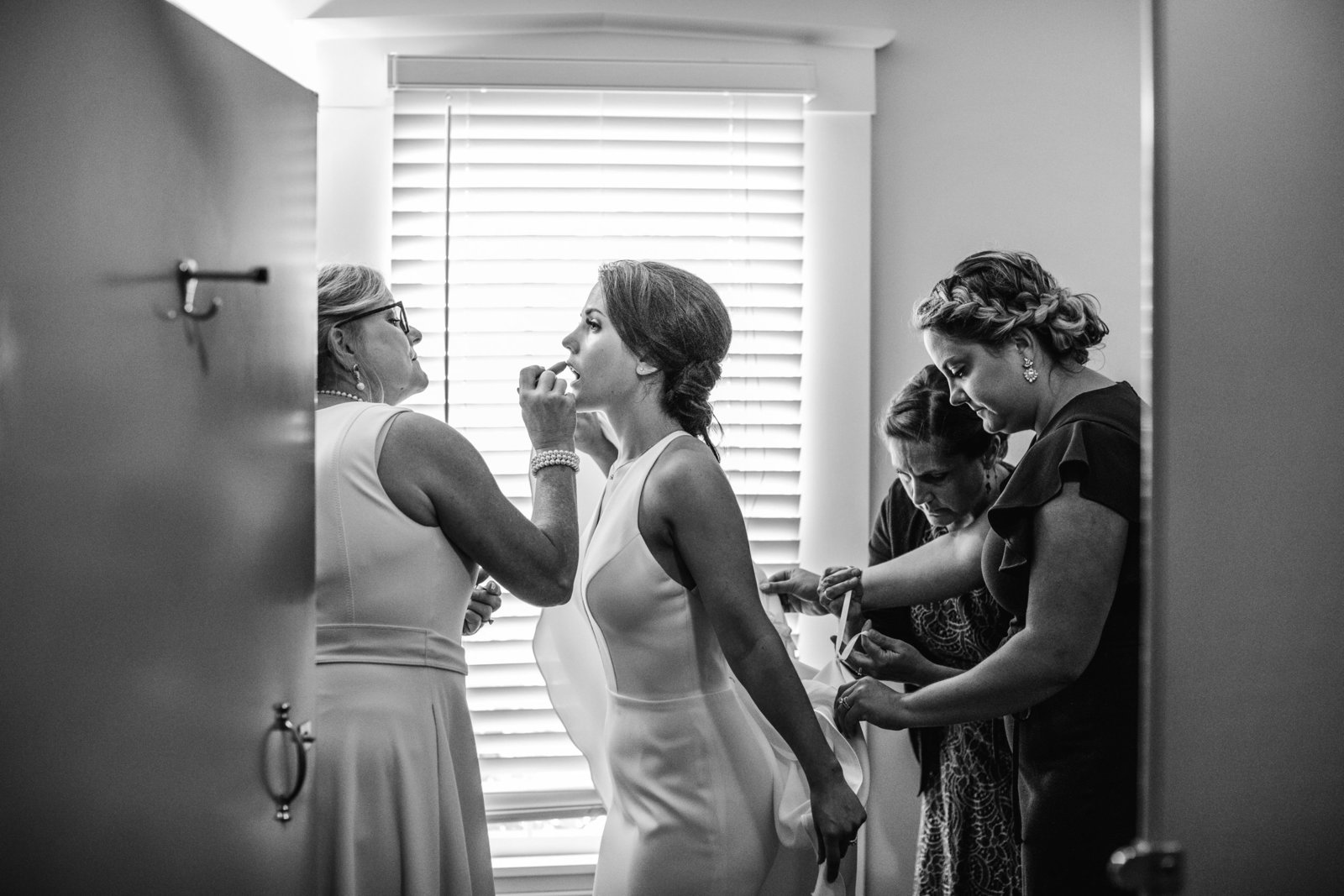 women help bride prep for her wedding in the bathroom