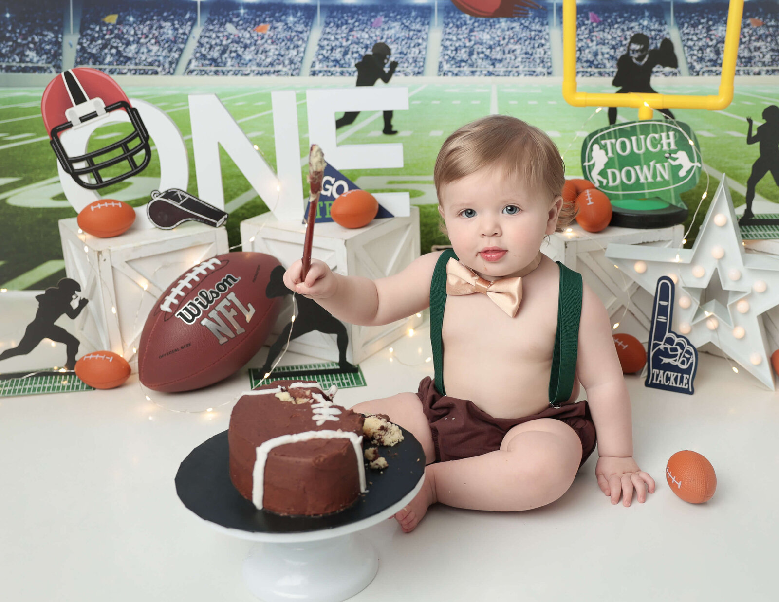 Cute one year old boy at his football themed cake smash in our Rochester, NY studio.