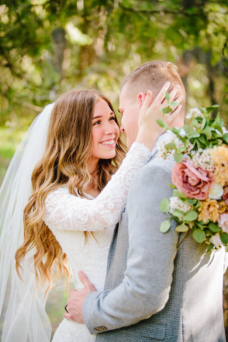Jackson Hole wedding photographers capture bride hugging groom holding bridal bouquet