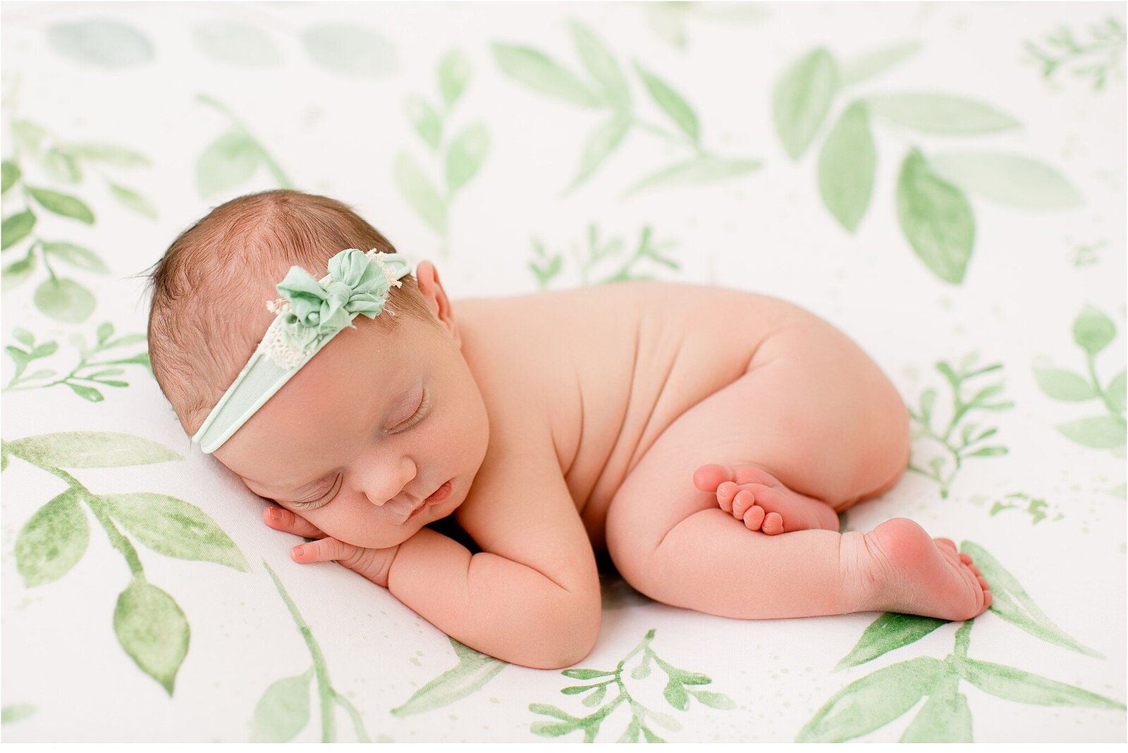 newborn baby on green leaf blanket