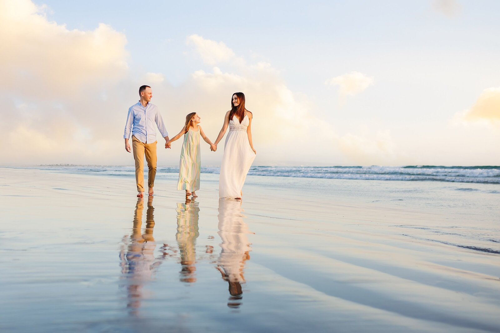 Girl with parents walking along the beach in Coronado
