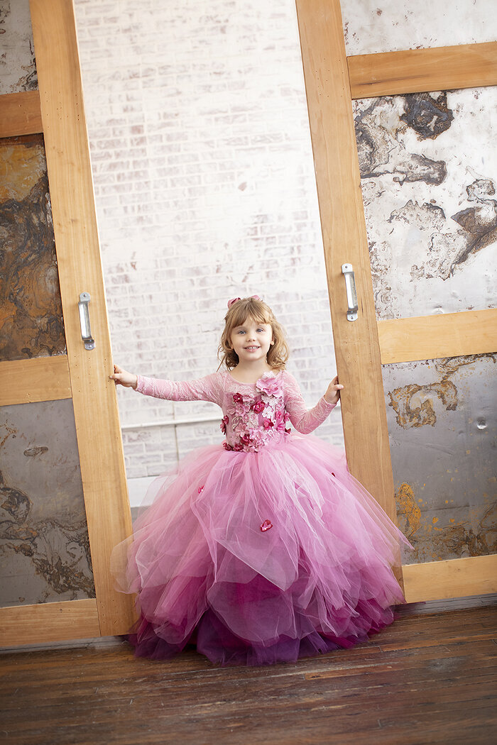 Young girl in gown standing between doors in Dallas photography studio