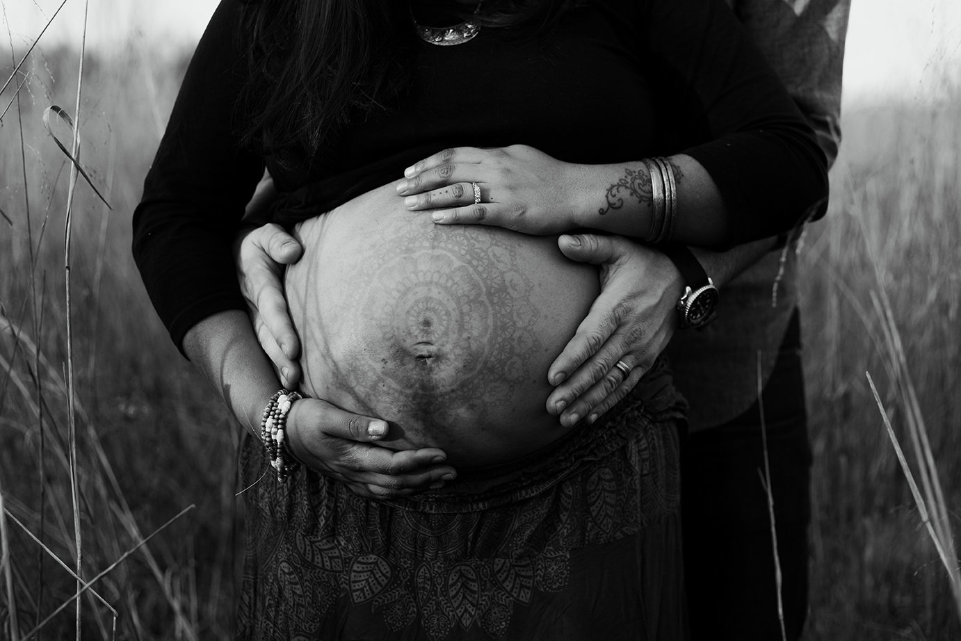 Parents placing hands on wifes belly during pregnancy maternity photo shoot