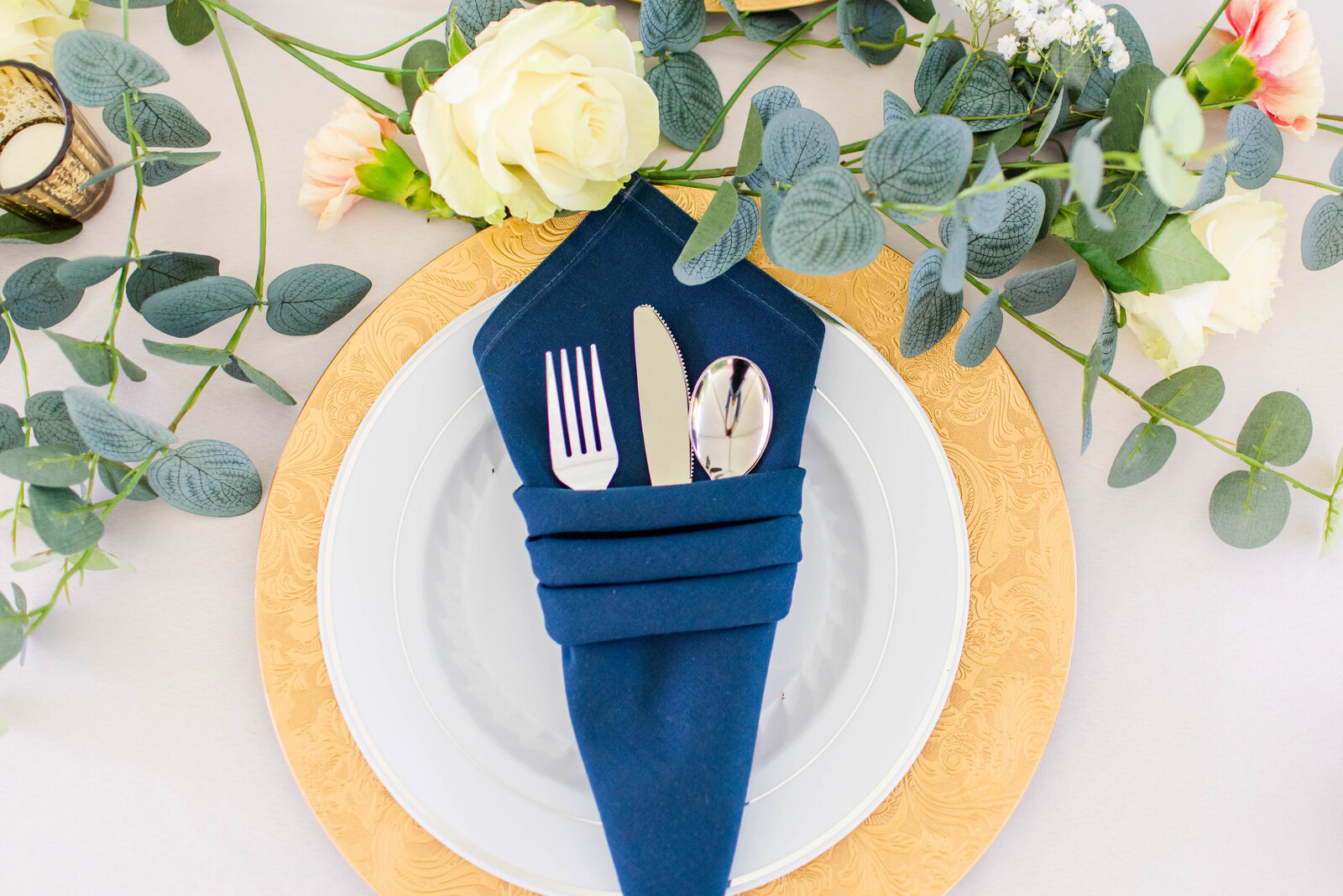 table setting with a blue napkin, silverware, and a white plate
