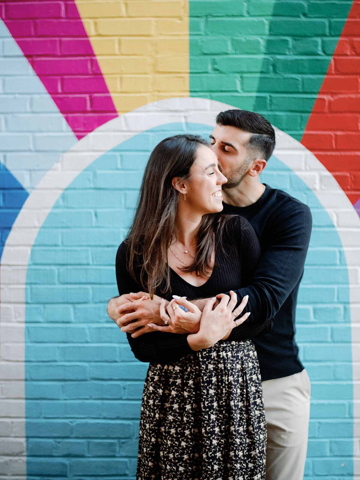 Photo in front of colurful mural in old town alexandria of couple embracing