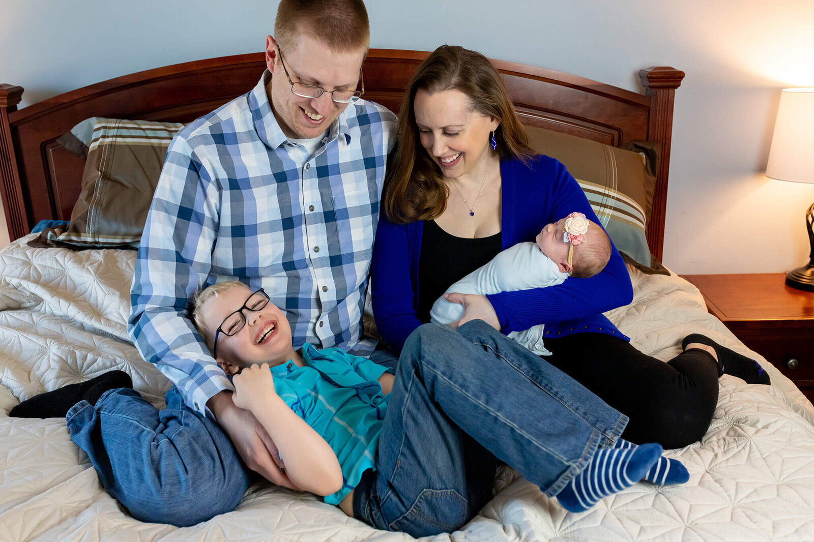 A family of four snuggling in bed in their Manassas home.