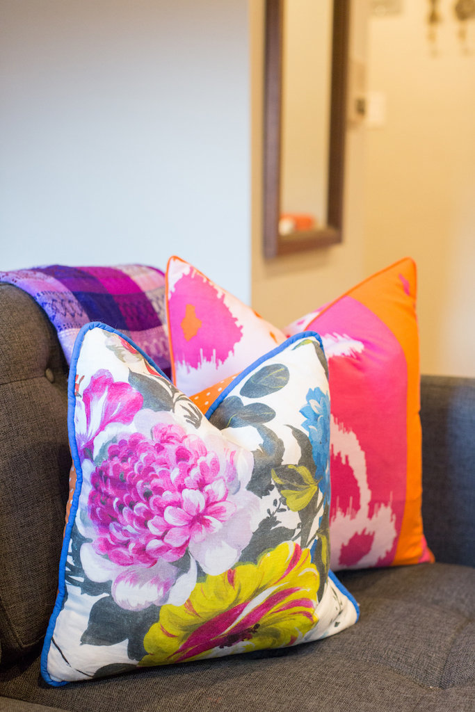 Bright and colorful throw pillows on a grey sectional.