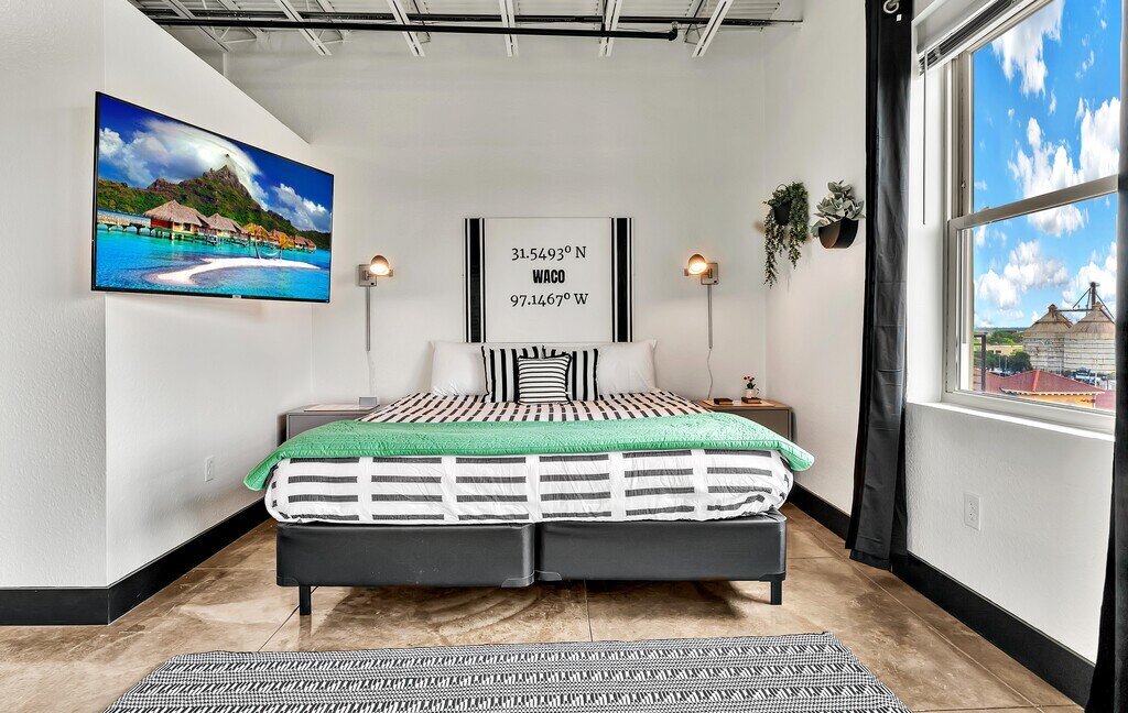 Bedroom with city view and Smart TV in this one-bedroom, one-bathroom vacation rental condo with sleeping space for four is walking distance from the Silos, McLane Stadium, and Baylor University in downtown Waco, TX