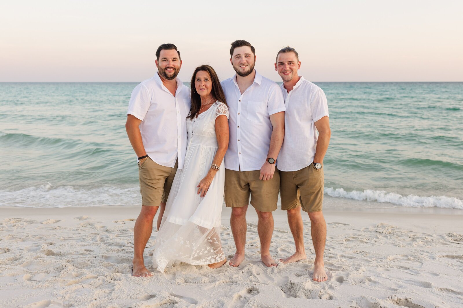 Mother with 3 adult sons posing during family beach trip to Pensacola, FL