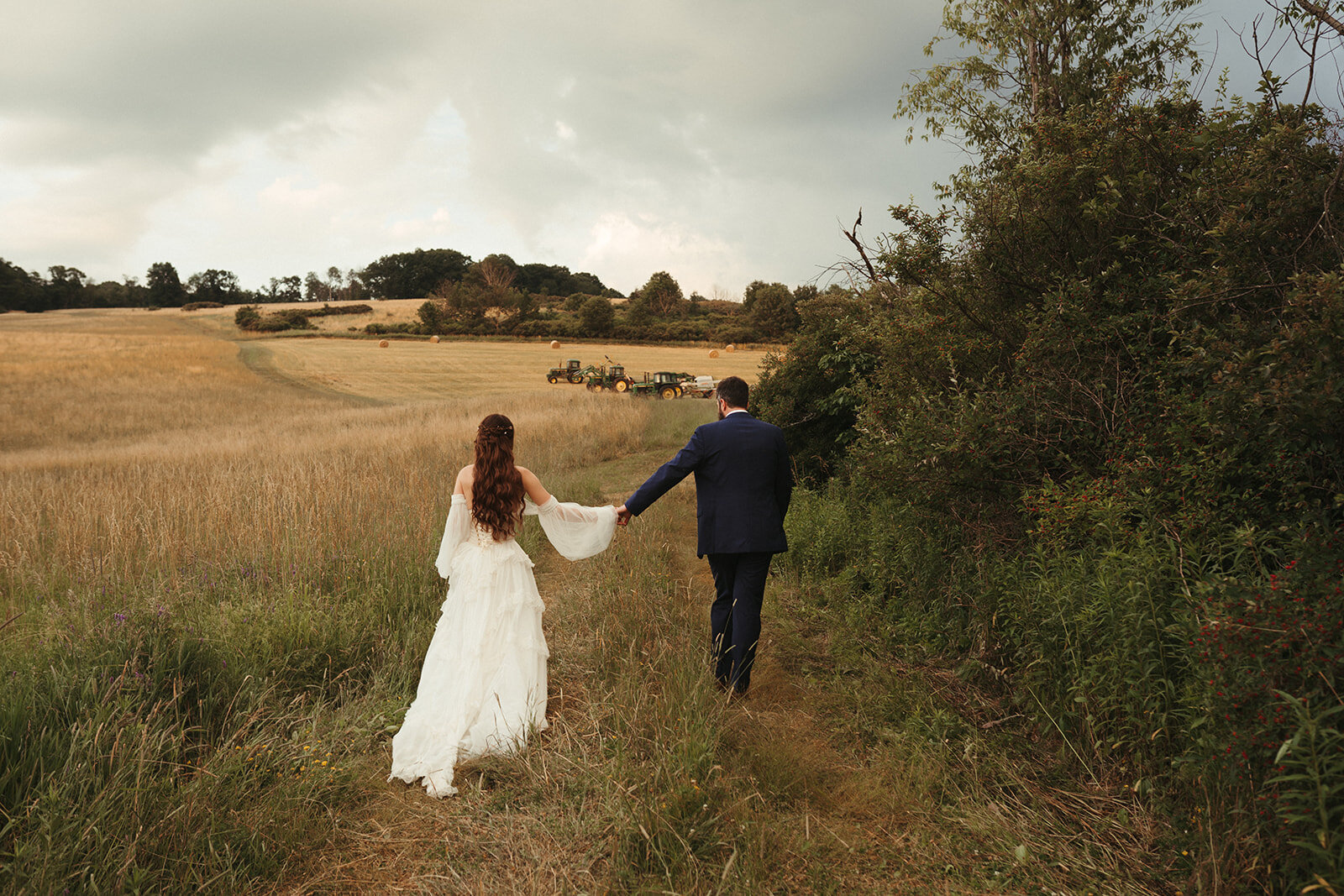 couple walking in field after wedding ceremony holding hands