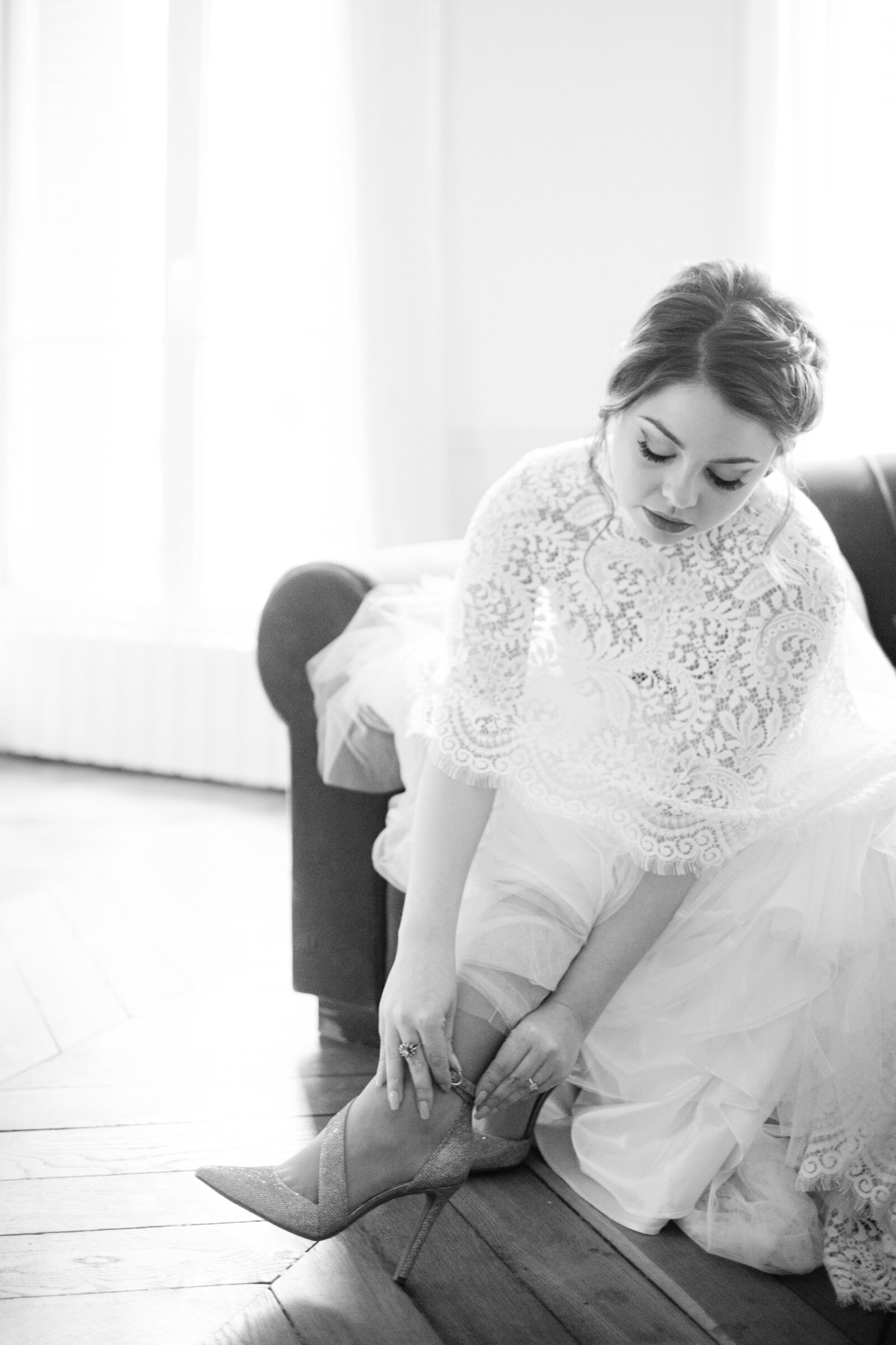 black and white photos of bride putting her shoes on