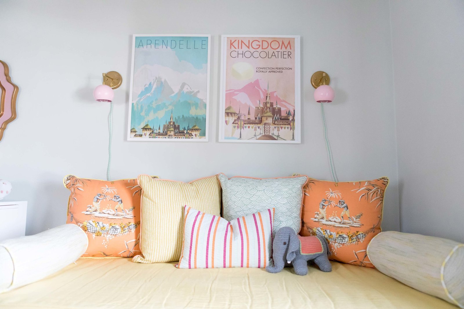 A day bed with colorful throw pillows and two framed posters.
