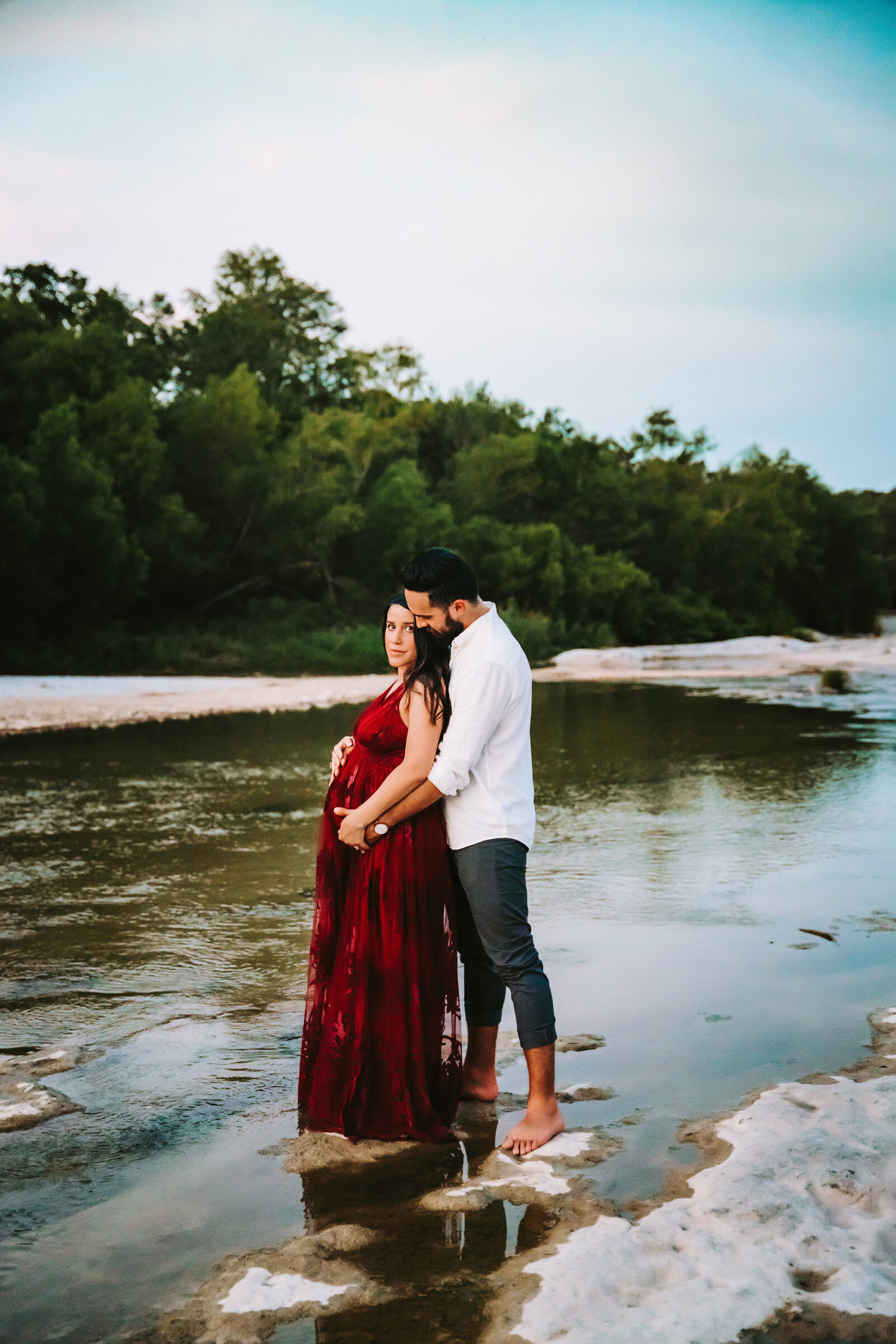 Maternity Photographer, a husband hugs his pregnant wife in a quiet river