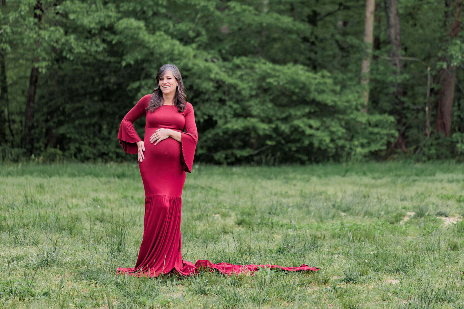 An outdoor Burke, VA maternity portrait session of a woman in a red dress.