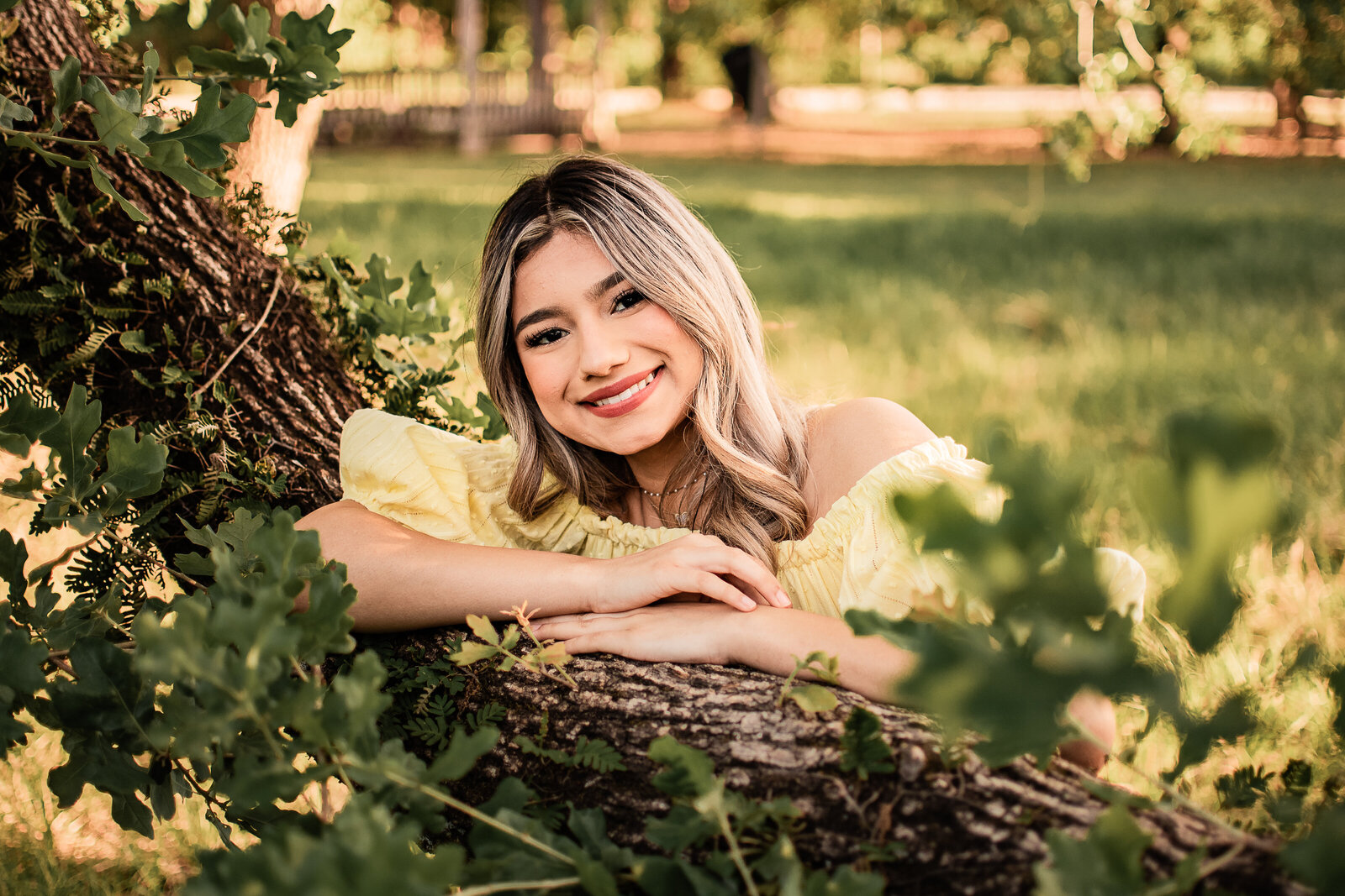 A Houston area senior leans on an oak tree covered with vines and smiles at the camera.