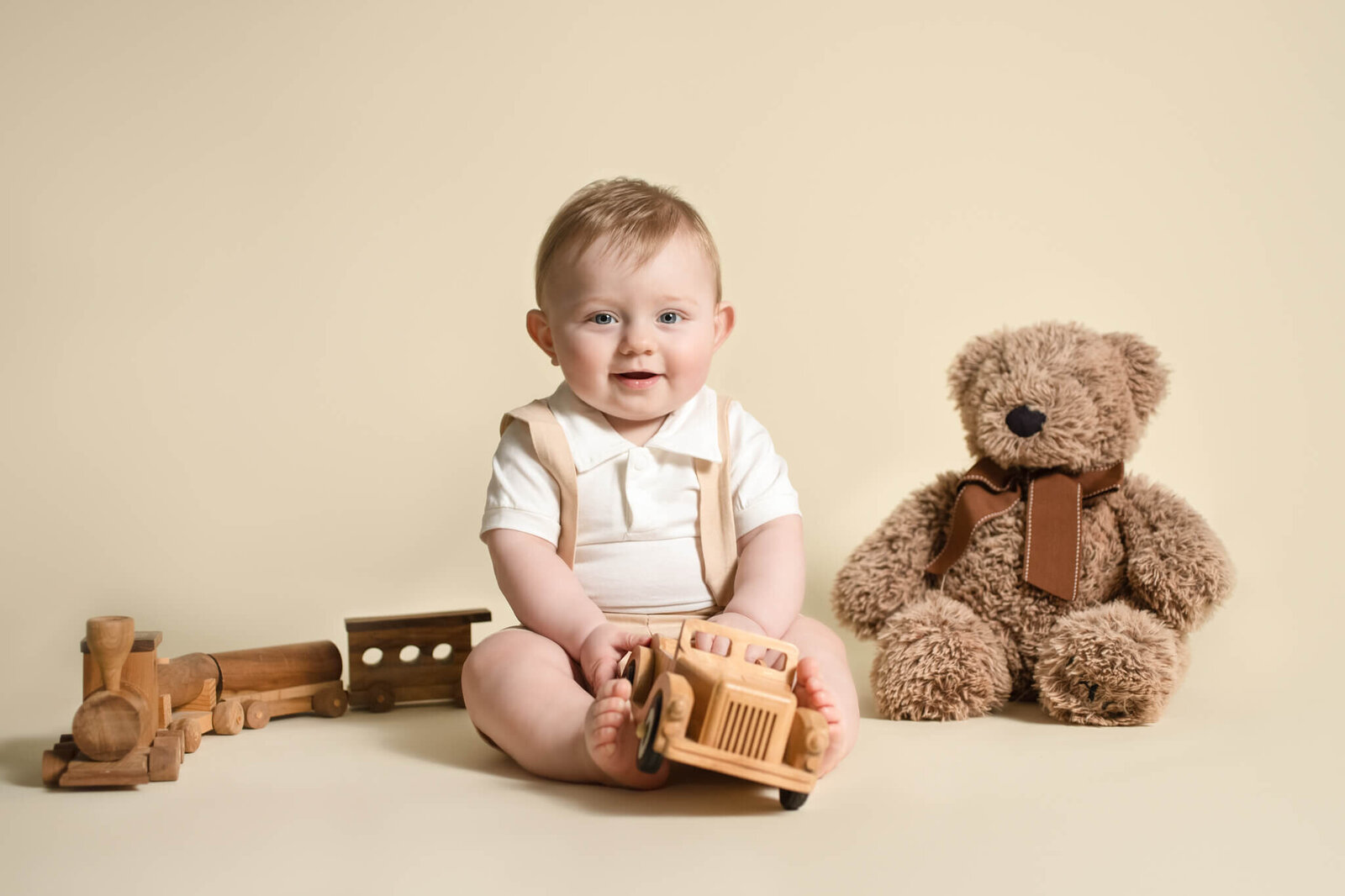 Six month sitter session of little boy wearing tan outfit holding wooden car