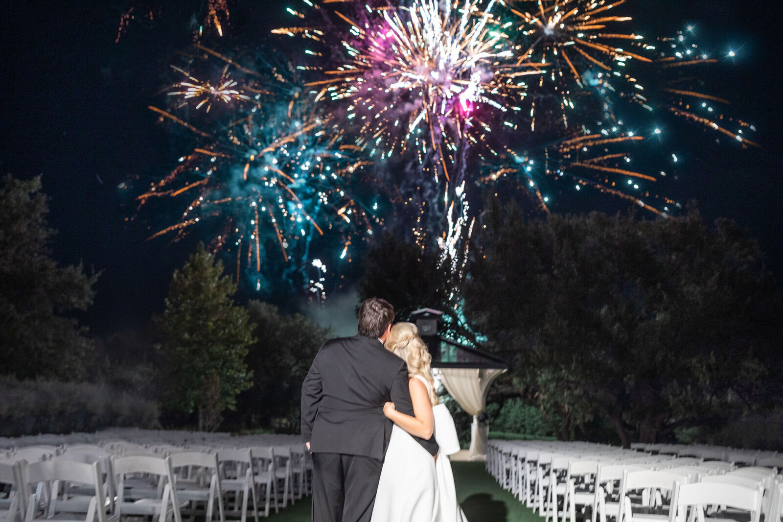 Bride and groom watch fireworks during their wedding reception.