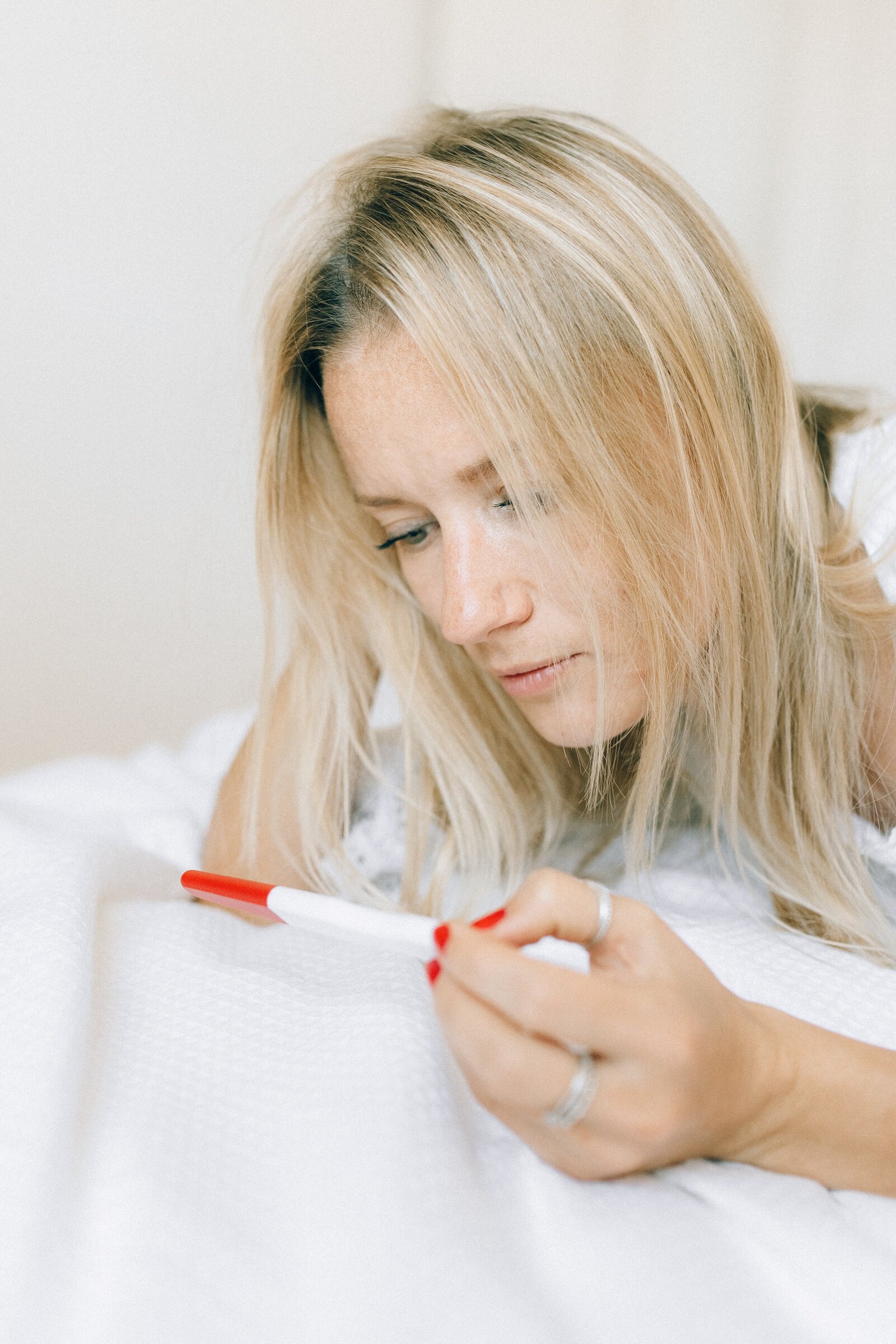 Woman sadly looking at home pregnancy test.