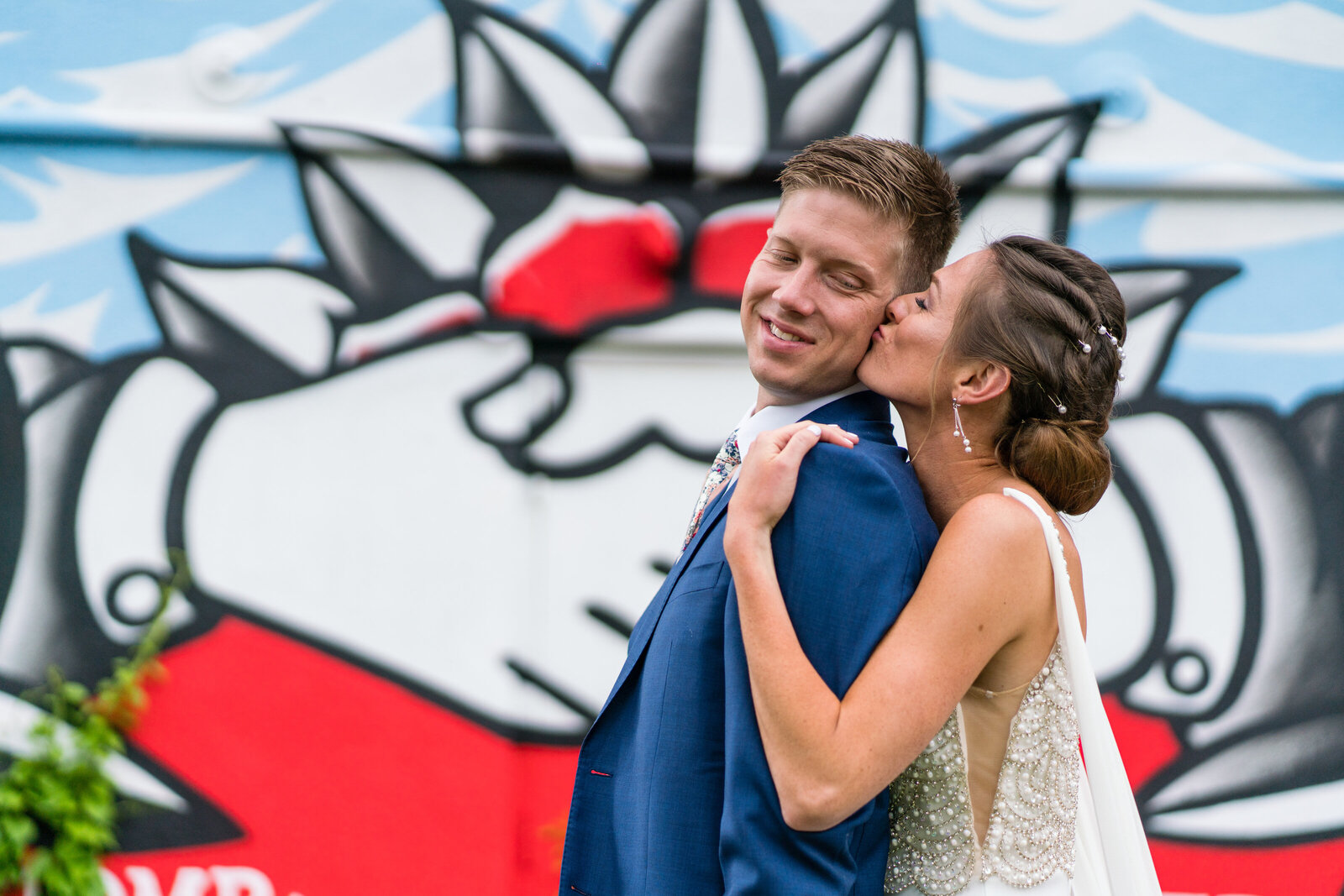 bride and groom pose in front of new bedford mural