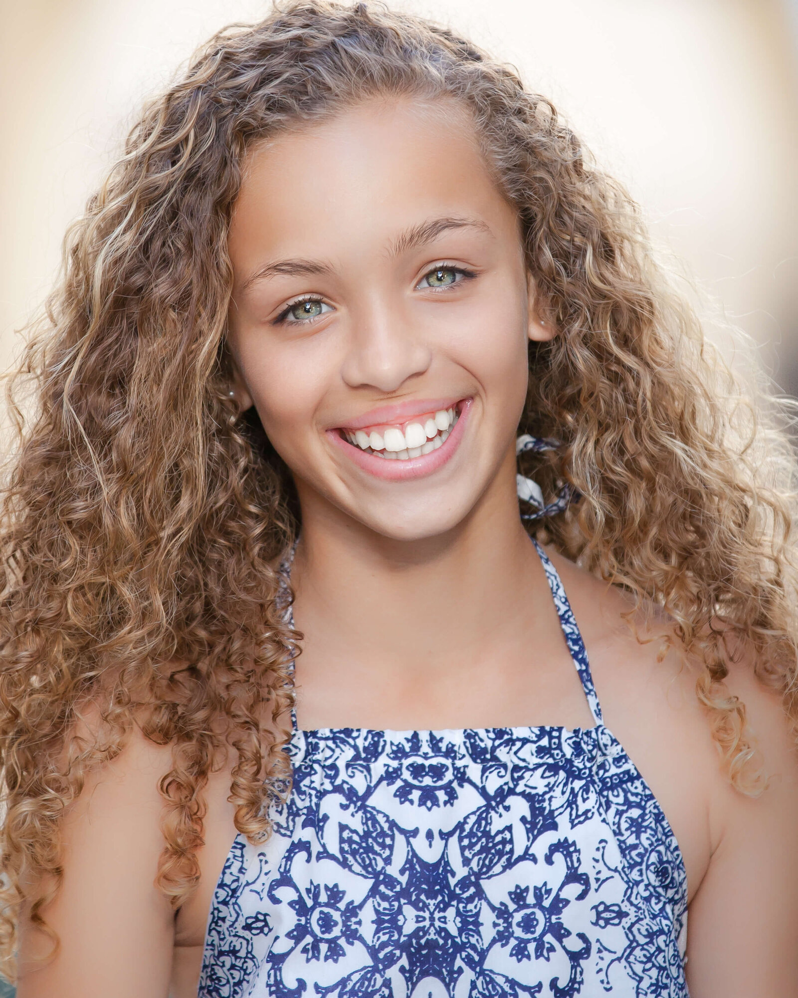 Actor headshot session in Orlando, Florida, capturing a young woman with curly hair. Natural light photography emphasizing expressive eyes and a charismatic presence.