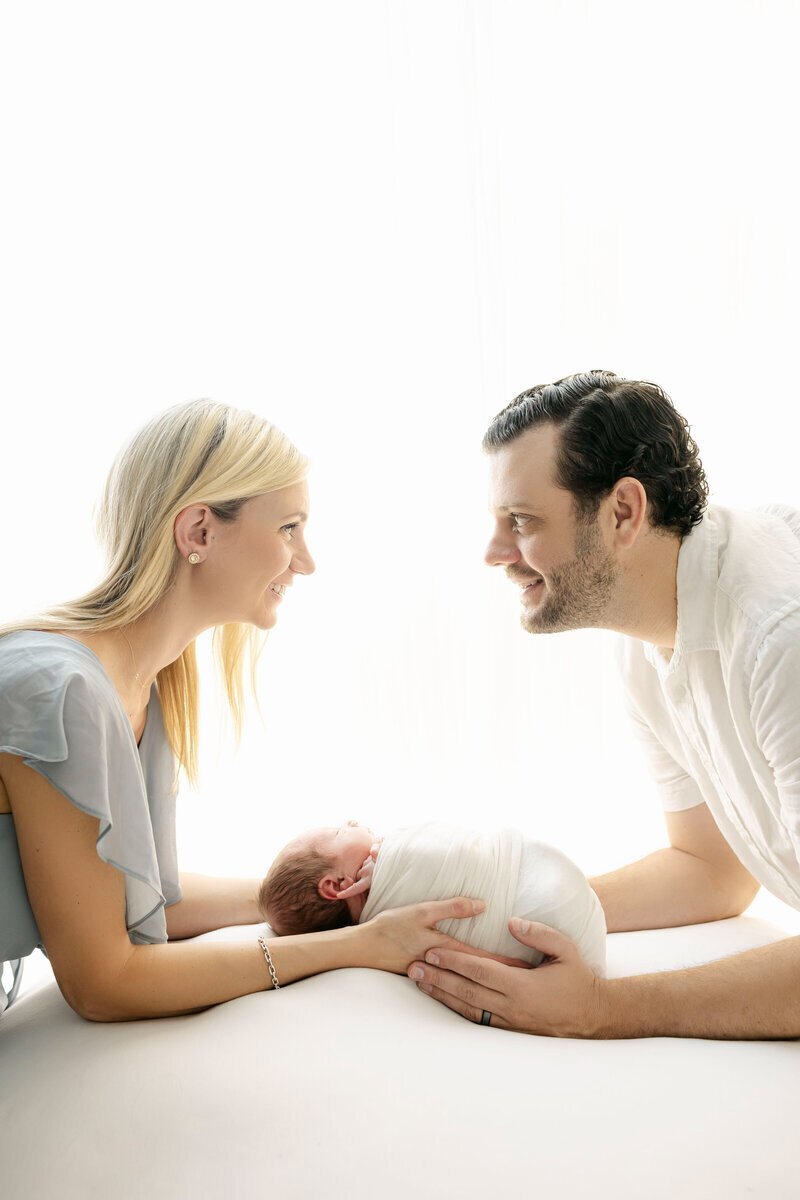 New parents looking at each other and holding baby taken by newborn photography in new jersey
