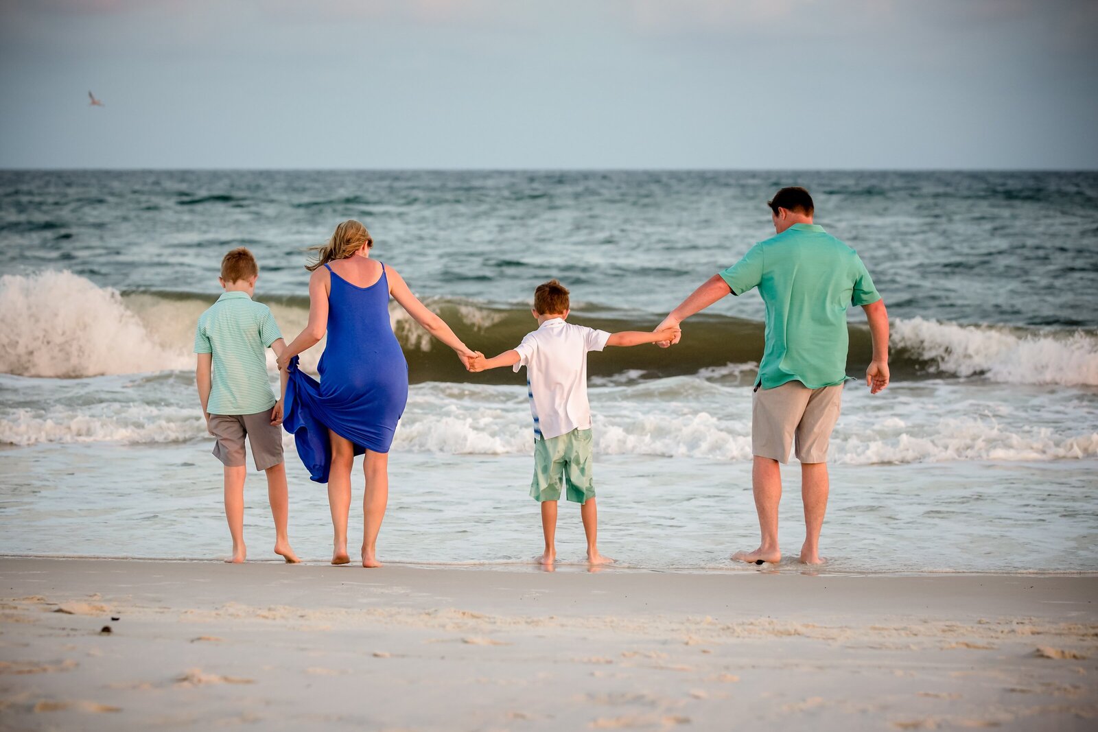 Pensacola Photography session during family vacation on Pensacola Beach . Family playing together in the water at sunset.