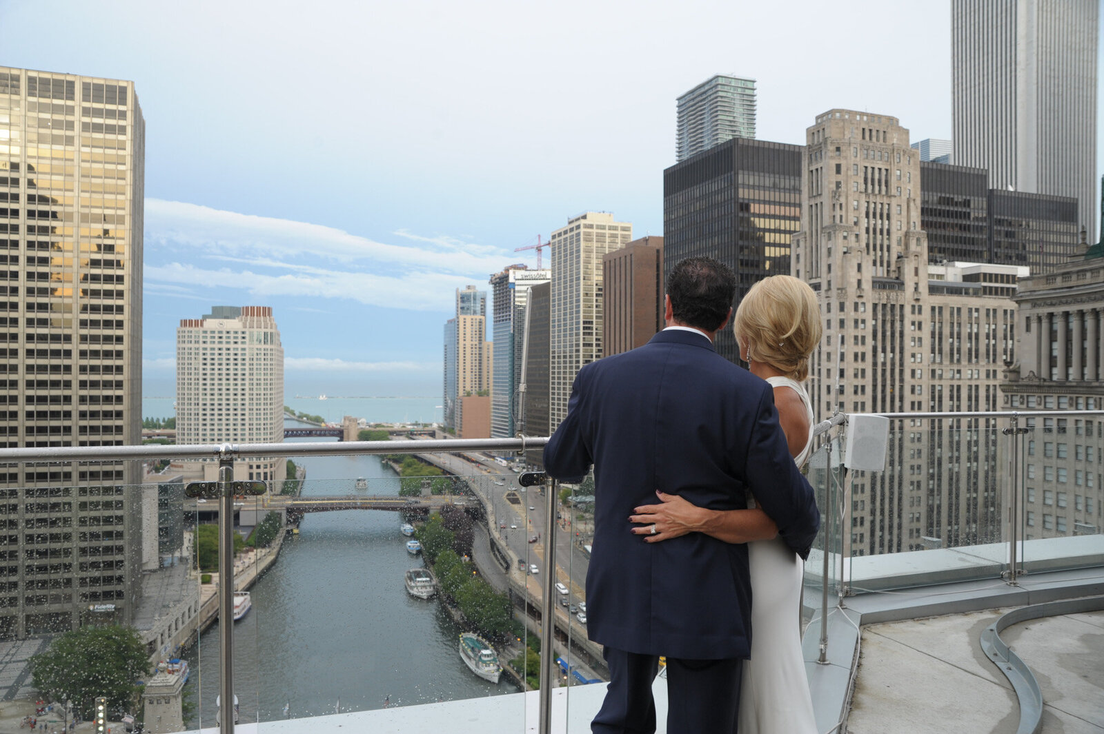 Couple on top of a building looking at a beautiful view that has tall buildings, river and bridge
