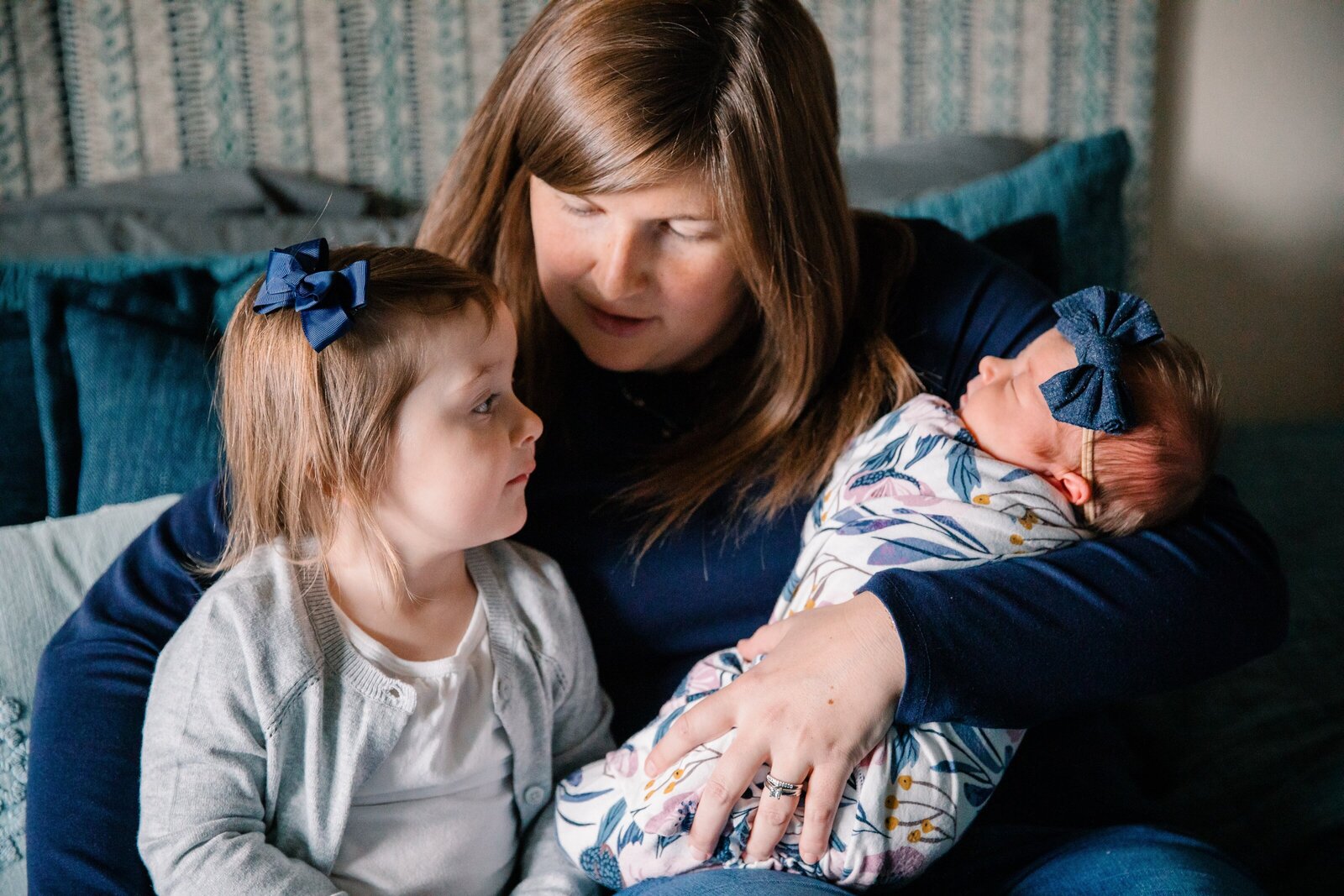 Mama holding two daughters during newborn family session.