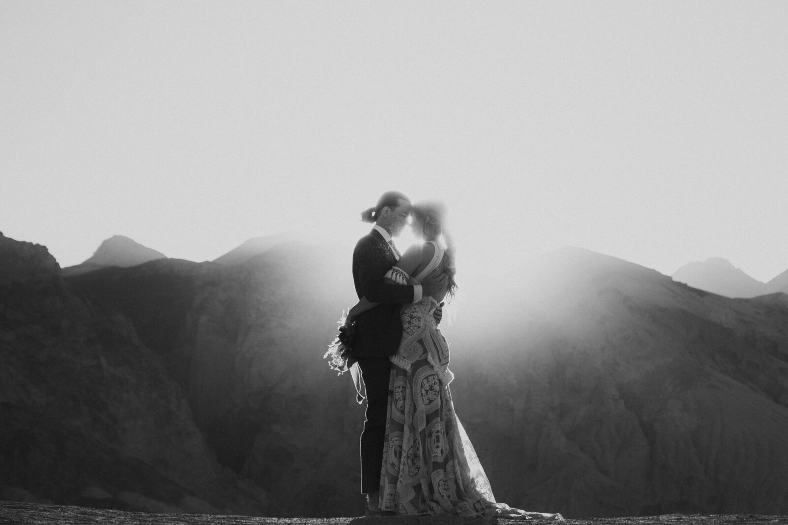 Black and white photo of a couple holding each other during their elopement at sunrise in Death Valley.