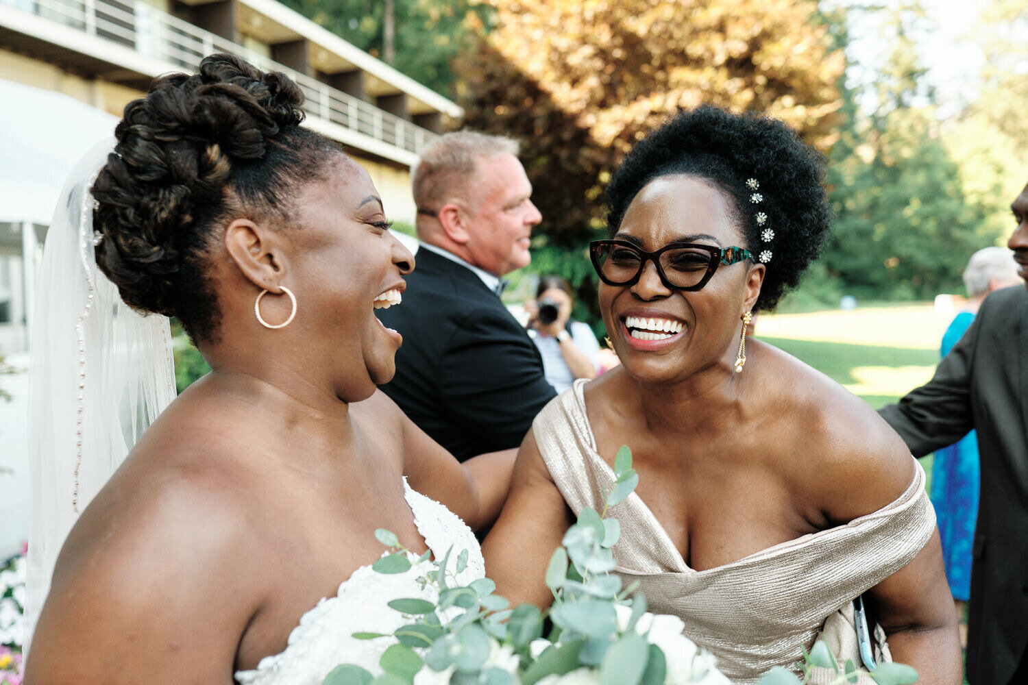 Bride and wedding guest laugh together after the wedding ceremony
