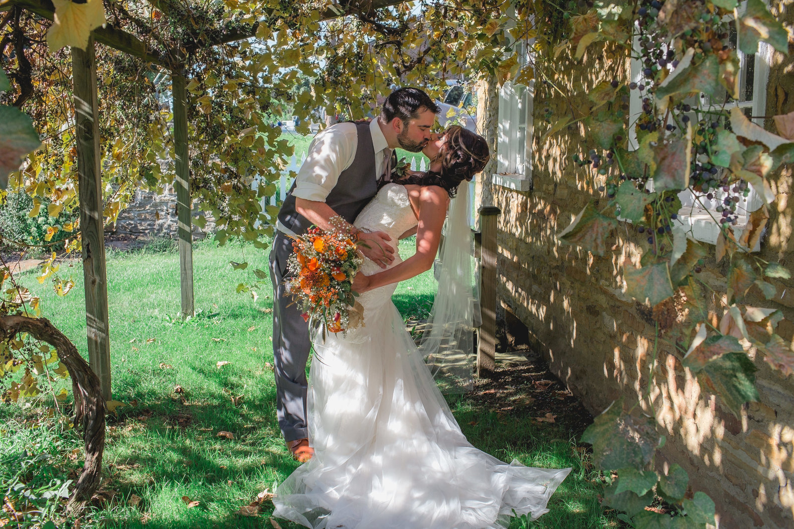 groom dips bride for a kiss under the romantic grapevines near a cabin at west overton