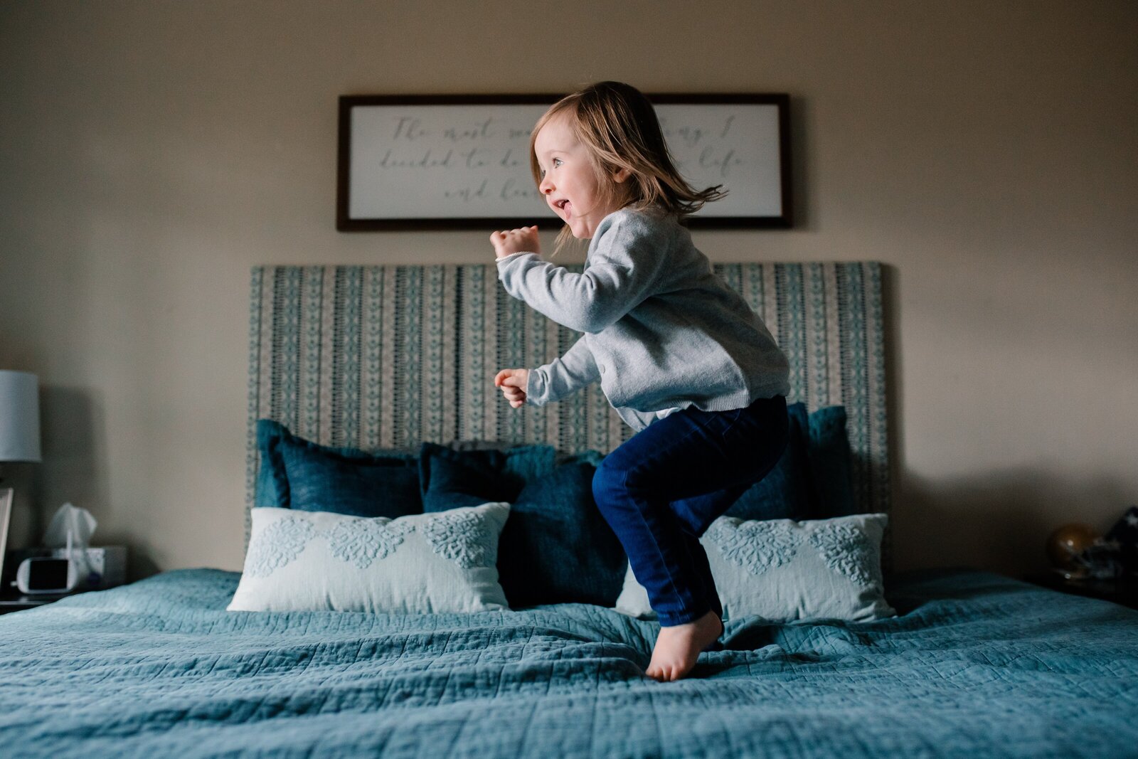 3 year old jumping on bed during family photo session.