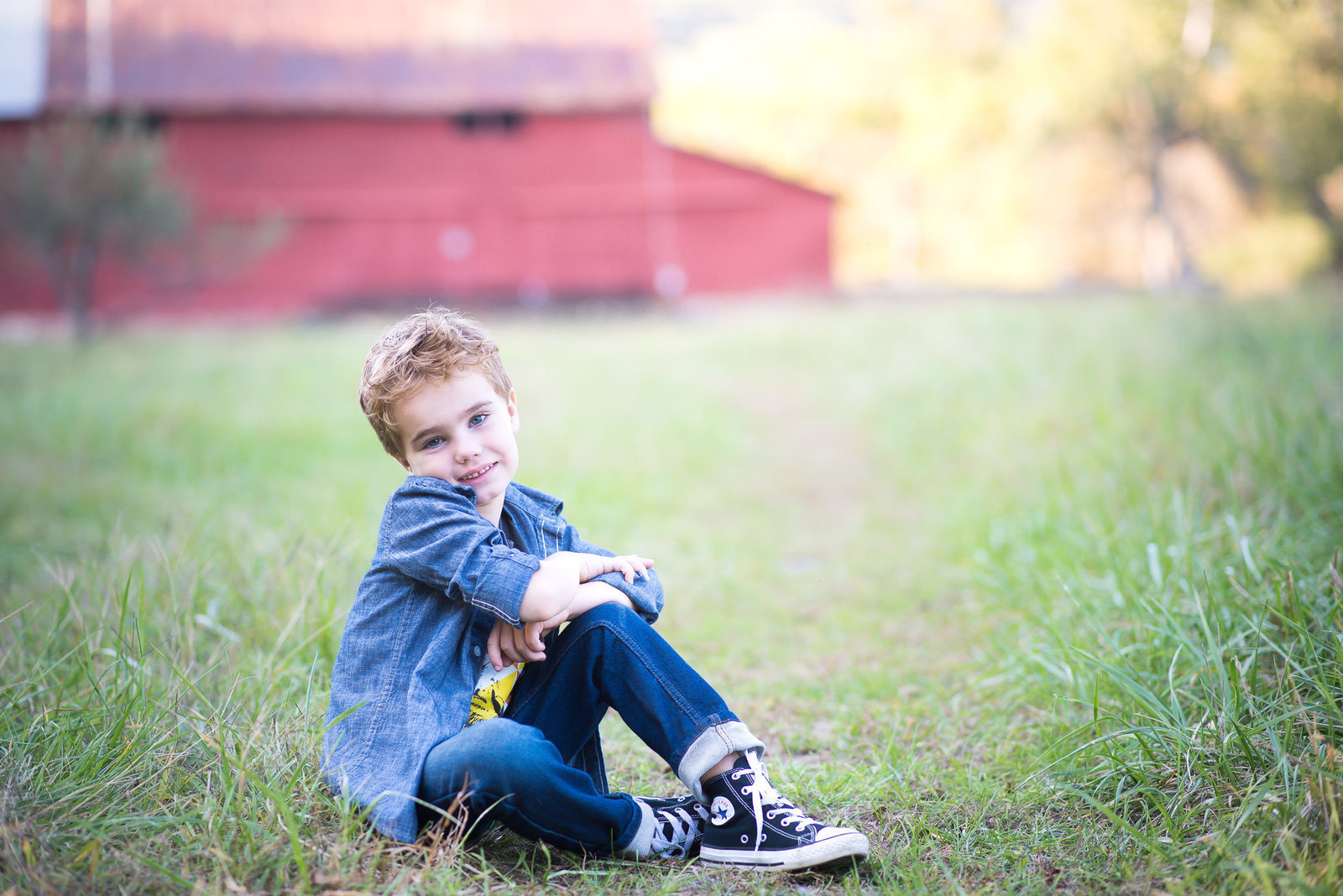 Portrait photography of a handsome  boy sitting in front of red barn in Charlottesville.