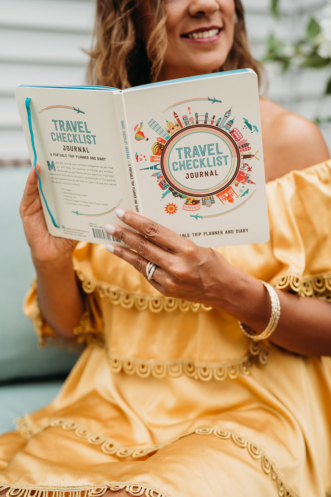 woman holds travel journal in a yellow dress
