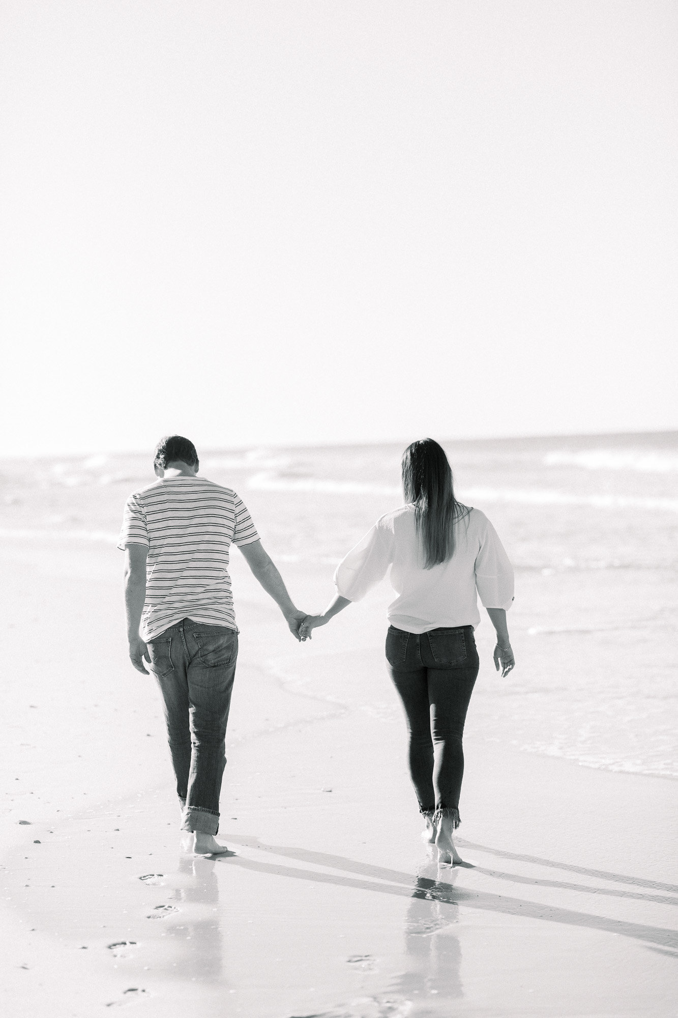 Holding hands on the beach captured by Staci Addison Photography
