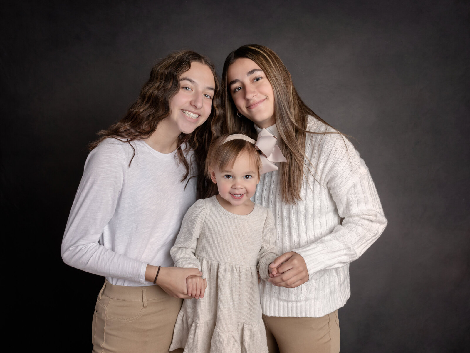 three sisters posing for studio family portraits