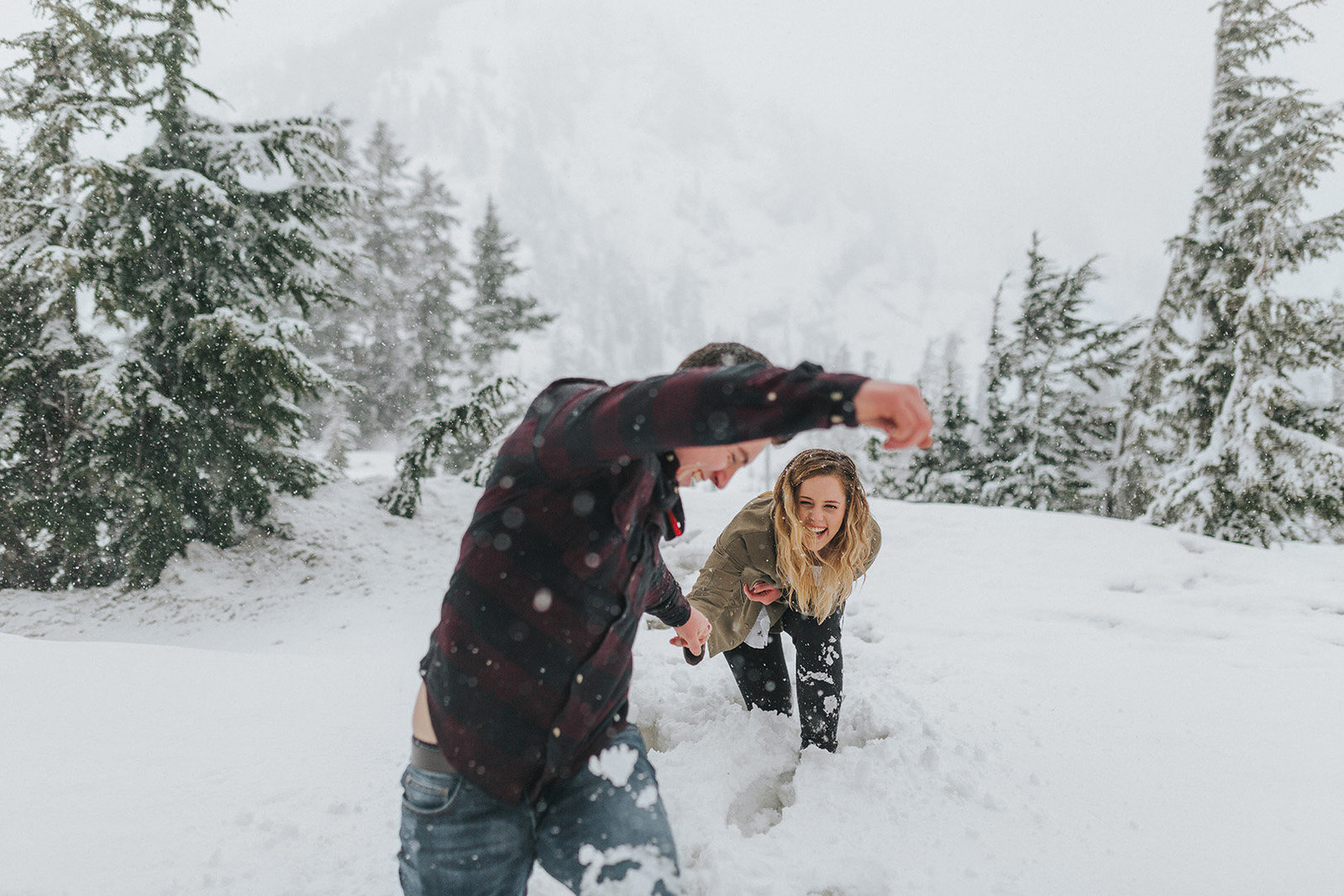 happy engaged couple running through the snow at Mount Baker engagement session