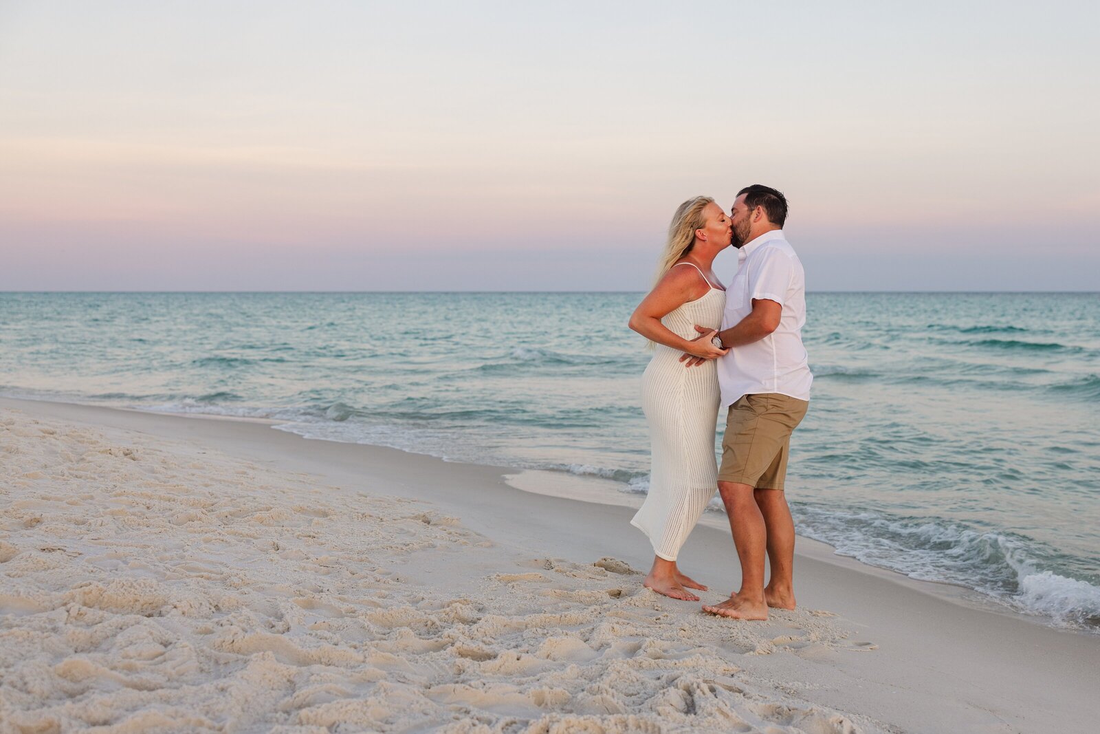 Maternity photo pose of couple kissing on Pensacola Beach