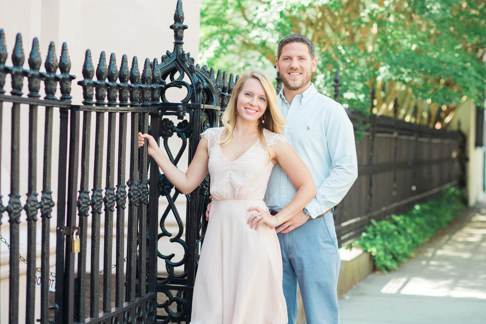 Engaged couple poses by wrought iron gate of Huguenot Church in the French Quarter, Downtown Charleston, South Carolina