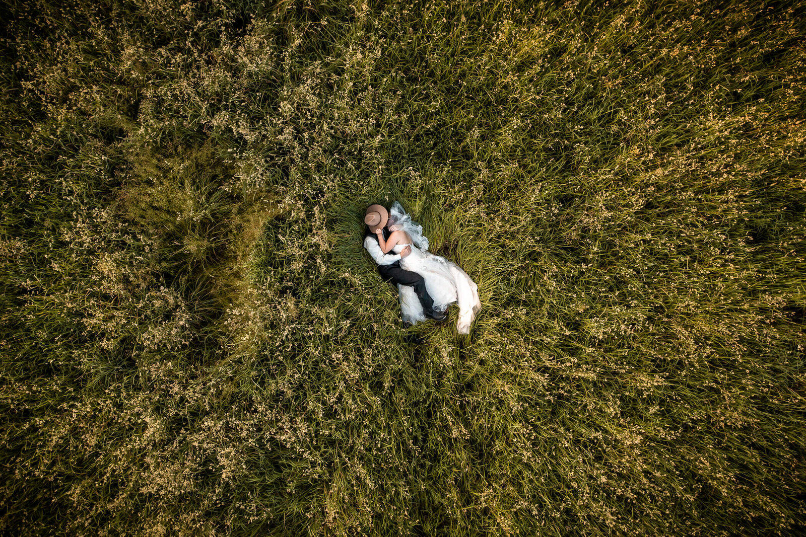 Pennsylvania wedding photo of a bride and groom holding each other in a field of grass, captured by a drone at their barn wedding venue in Pennsylvania