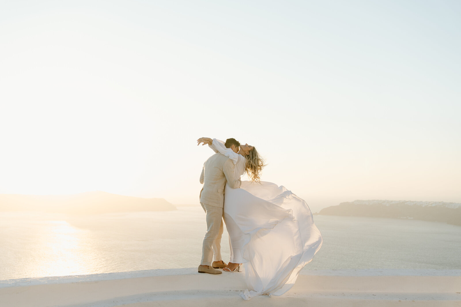 Couple in wedding attire elopeing on a rooftop in Santorini Greece