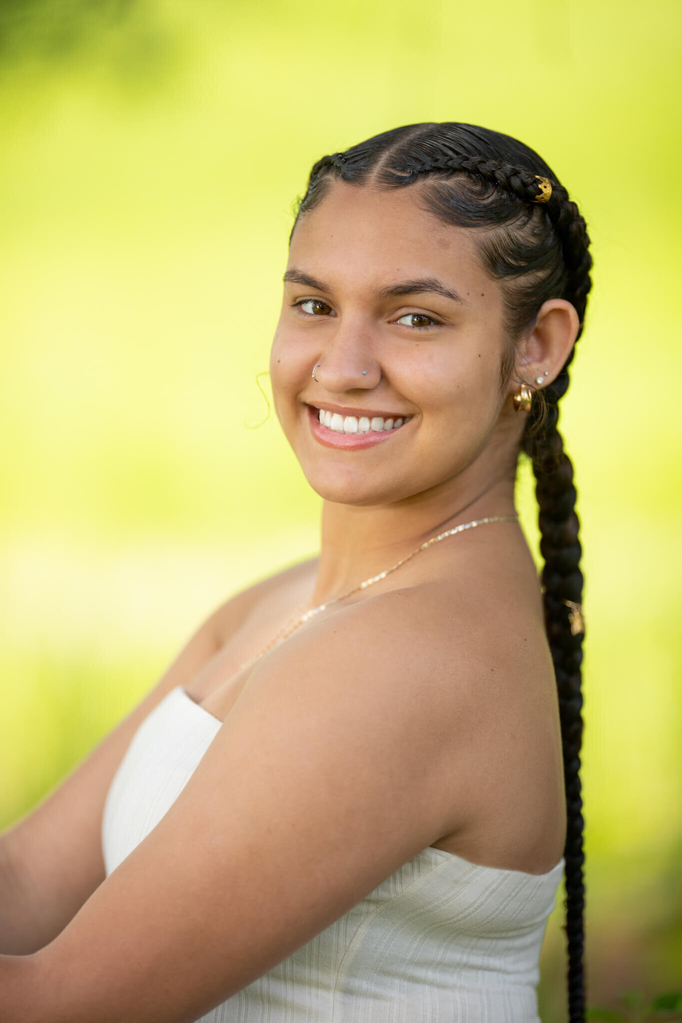 High school senior portrait photography in Clinton MA  of female in a white top smiling at the camera with a green and yellow background