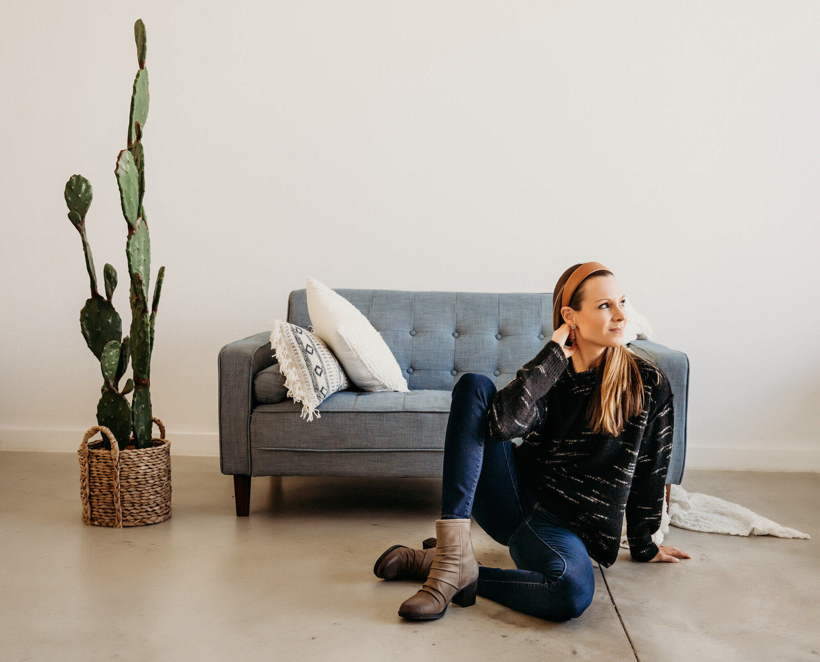 Branding Photographer, a woman sits on the floor beside a couch and cactus plant