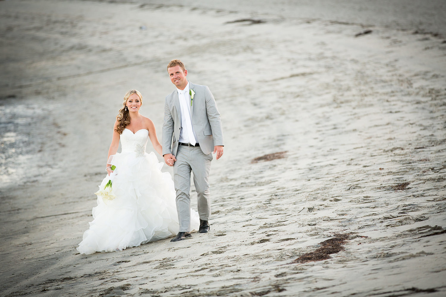 bride and groom in sand walking on beach
