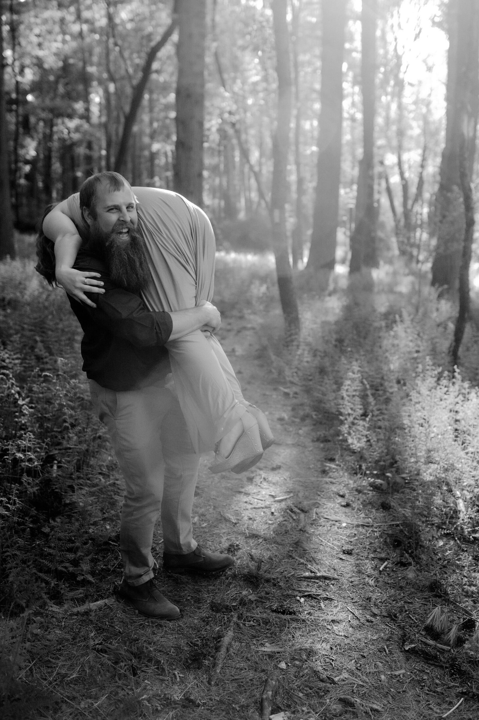 person being carried over partner’s shoulder laughing in the forest