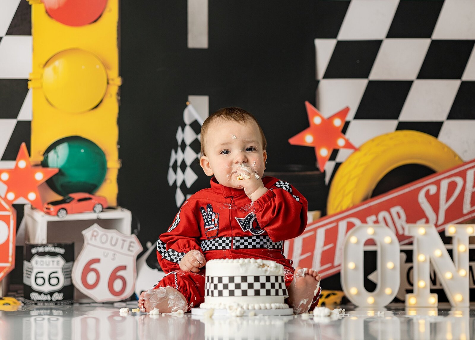 Baby boy eating a cake with a race car themed set.