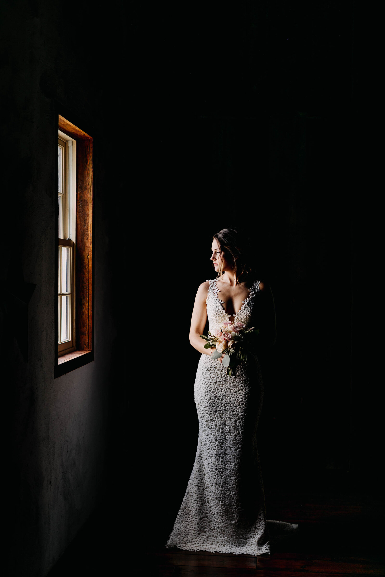 bride looking out window with moody light