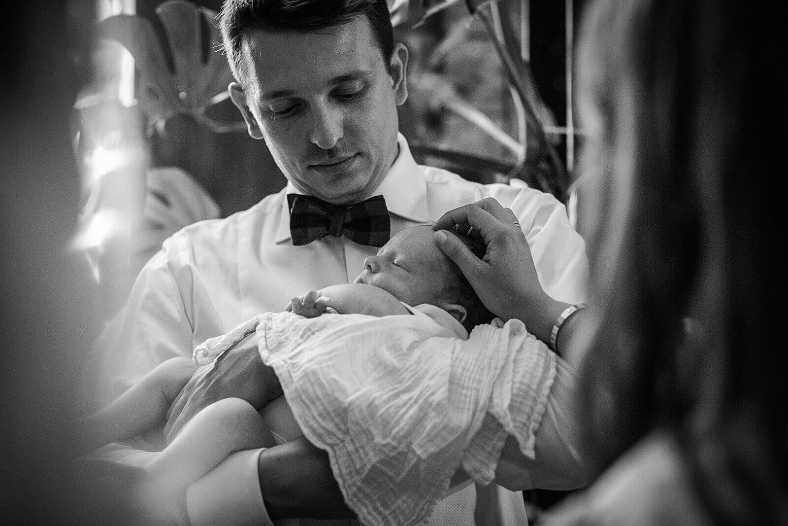 Groom holds baby in his arms at London wedding reception