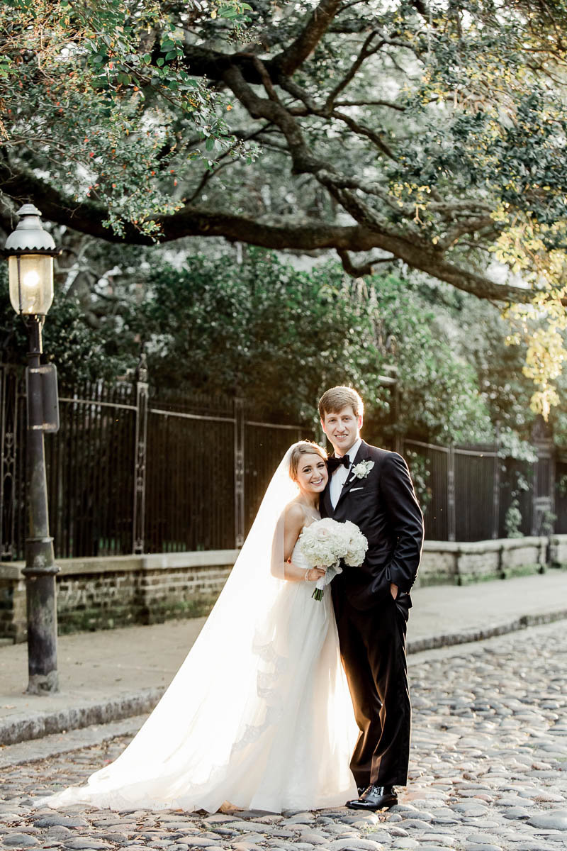 Bride and groom stand on the cobblestones of Washington Square, Charleston, South Carolina. Kate Timbers Photography.