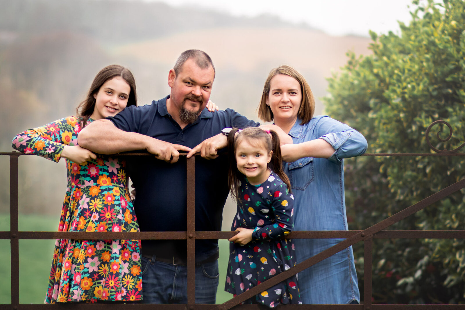 Family of four stand at field gate for photoshoot in Devon